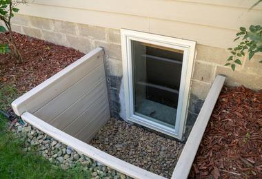 New egress basement window installed in a residential foundation with a window well