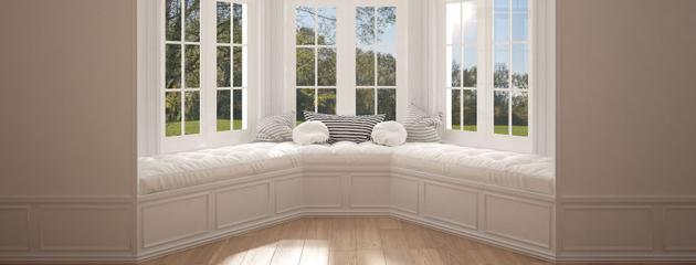 Minimalist home interior with a large bay or bow window overlooking a garden meadow panorama