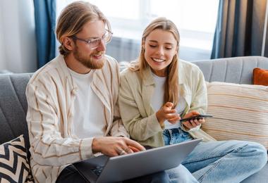 Homeowners researching replacement windows online using a laptop at home in Canada.