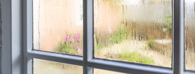 Condensation and water droplets on old window panes in a Canadian home, showing common crying windows caused by indoor humidity and cold glass.