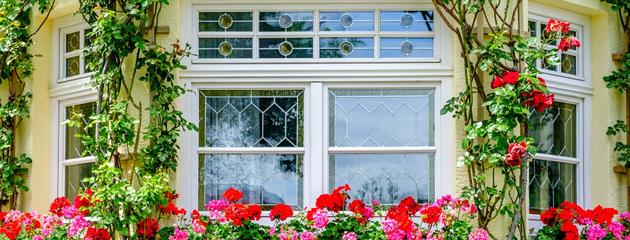 Traditional English cottage-style window on a stone home exterior with classic proportions and decorative detailing.