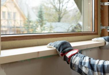 Handyman installing an exterior window sill as part of window sill replacement on a Canadian home