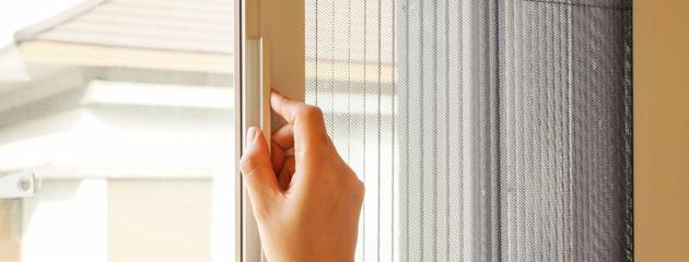 Woman opening retractable screen door in Canadian home for fresh air and insect protection