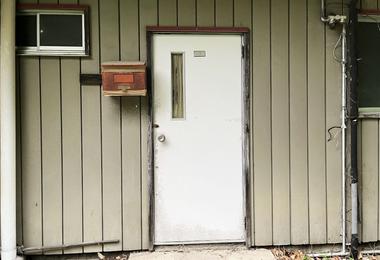 Older steel entry door showing visible wear, representing common issues like dents, rust spots, and alignment problems in Canadian climates.