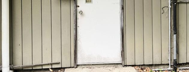 Older steel entry door showing visible wear, representing common issues like dents, rust spots, and alignment problems in Canadian climates.