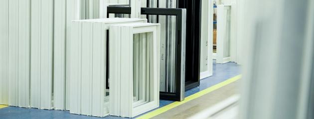 Vinyl window frames in a manufacturing facility showing different sizes and designs before installation