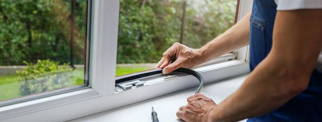 Worker installing sealing tape on a plastic window frame to prevent air and moisture leaks