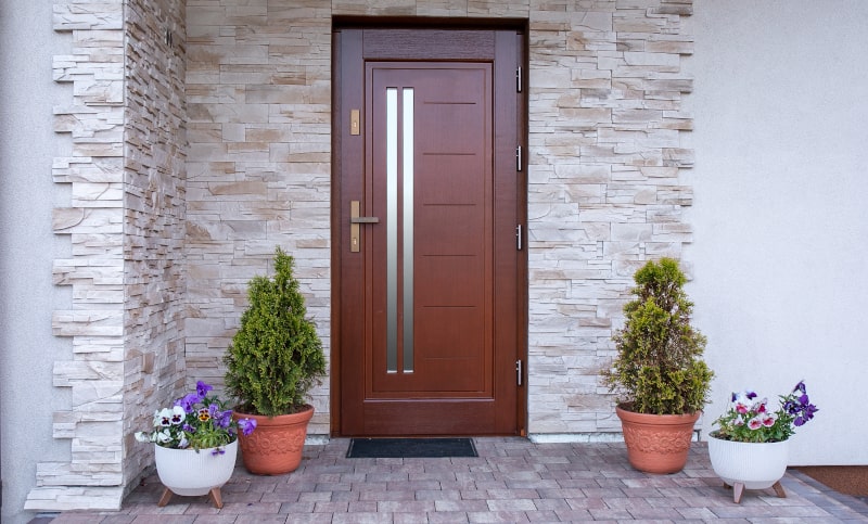 Brown double-entry door with stone accent wall in Canada