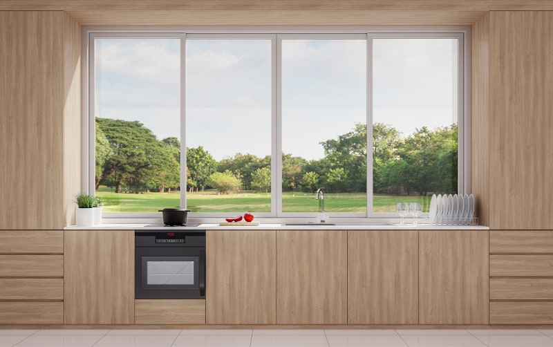 Modern wood-finish kitchen with large sliding windows and natural outdoor view