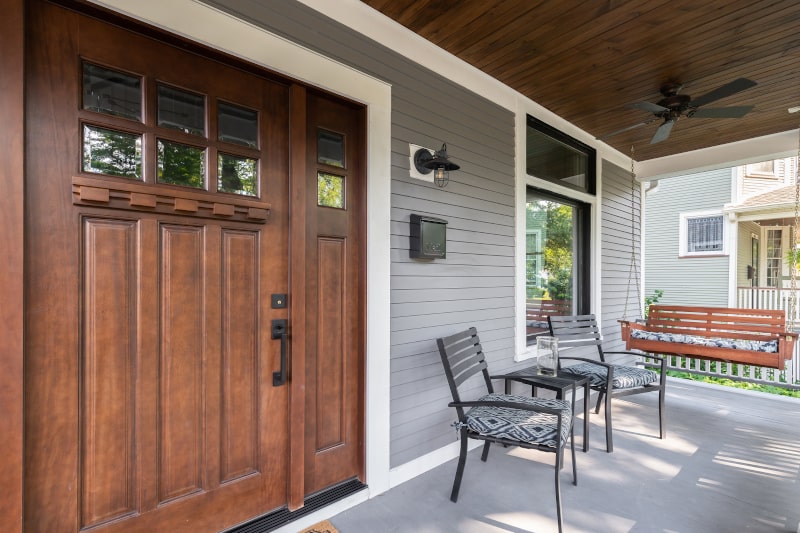 Classic wooden exterior door with glass insert on a grey home’s porch in Canada