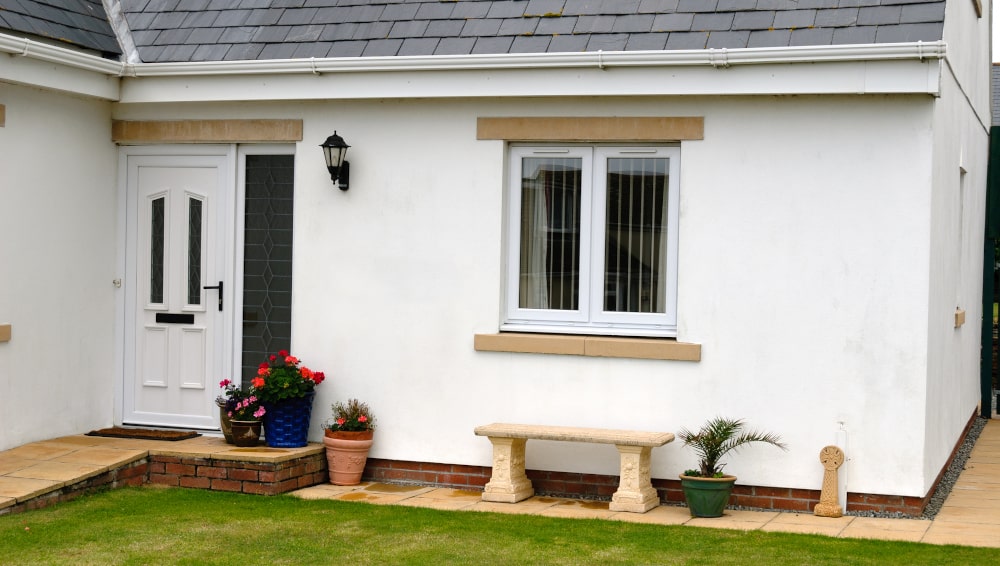 Casement cottage-style windows with decorative grilles on a Cornwall home, showing classic English countryside design.