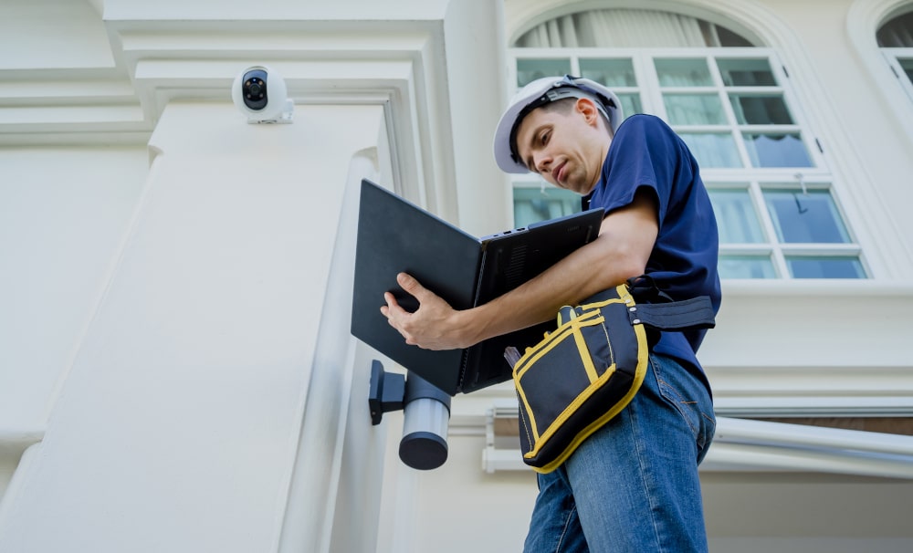 Technician working on exterior components of a home, illustrating inspection of safety features and potential entry points.