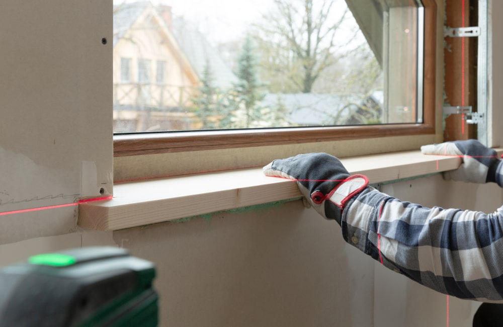 Contractor installing a new exterior window sill with the correct slope for water drainage