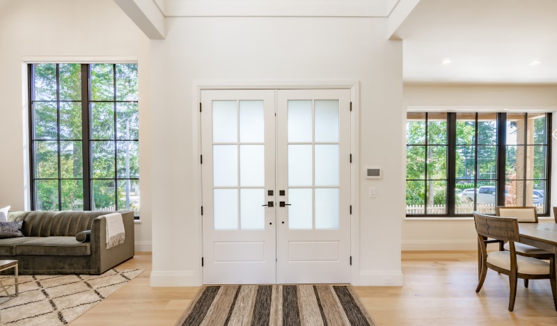 Traditional double French patio doors adding charm to a home’s exterior Elegant double French patio doors with glass panes and white wood frames opening to backyard