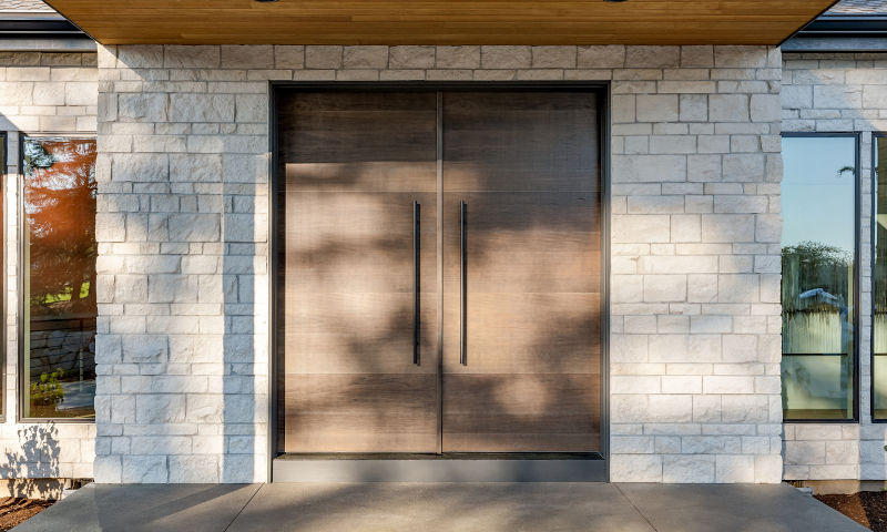 Brown steel front door with sidelites and covered porch on a Canadian home exterior