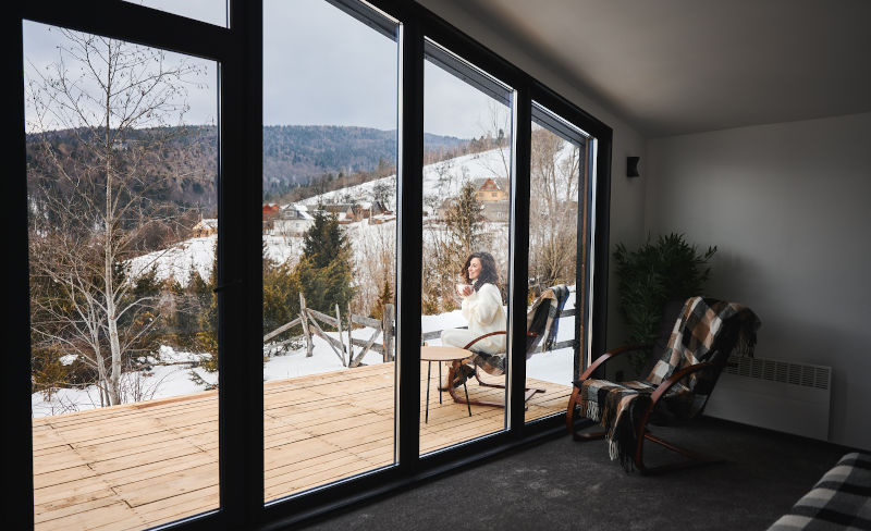 Outdoor winter terrace connected to a home through large bifold patio doors designed for cold climates.