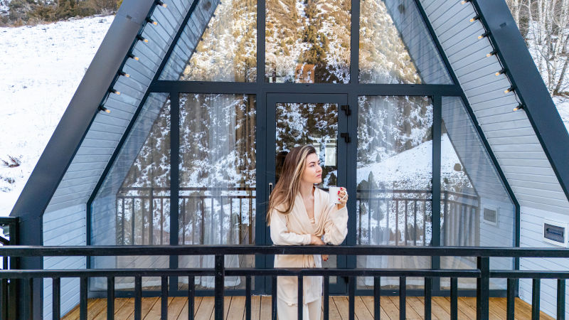 Modern cabin with large glass bifold patio doors overlooking a snowy landscape during winter.