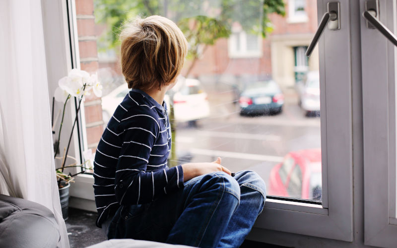 Child sitting by a window with a tablet, showing everyday interaction near a window and its hardware.