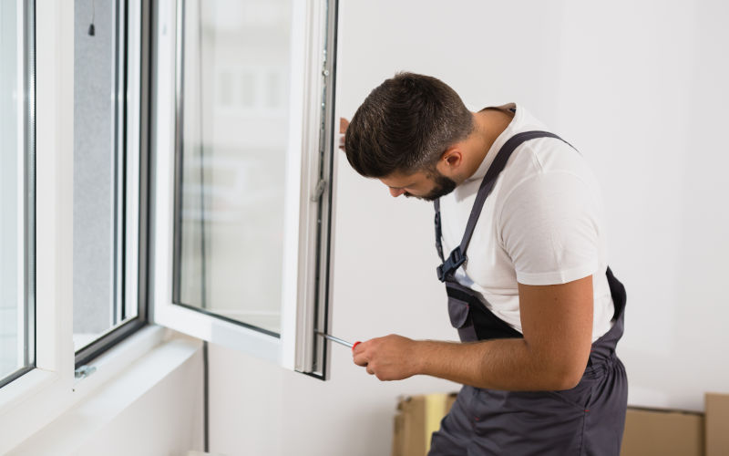 Man manually operating or maintaining a window at home, illustrating interaction with window hardware