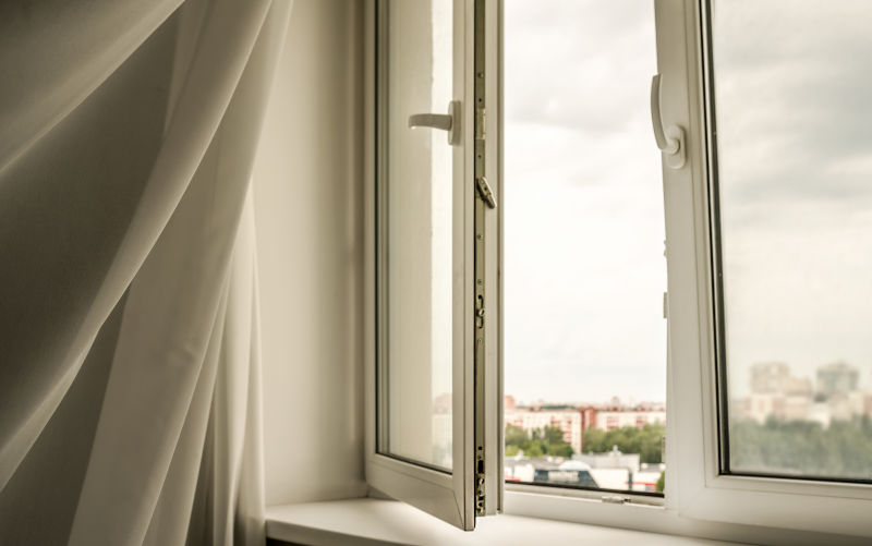 Open window with curtain blowing in the wind, showing air leakage and potential window damage in a Charlottetown home