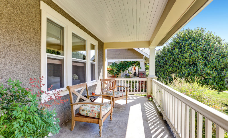 Modern home exterior with covered porch and large windows, illustrating durability and performance in residential window design