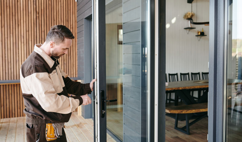 Technician performing maintenance on a sliding patio door inside a modern home