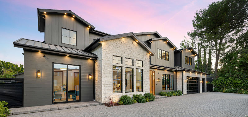 Modern grey home exterior featuring large premium vinyl windows and a backyard patio area
