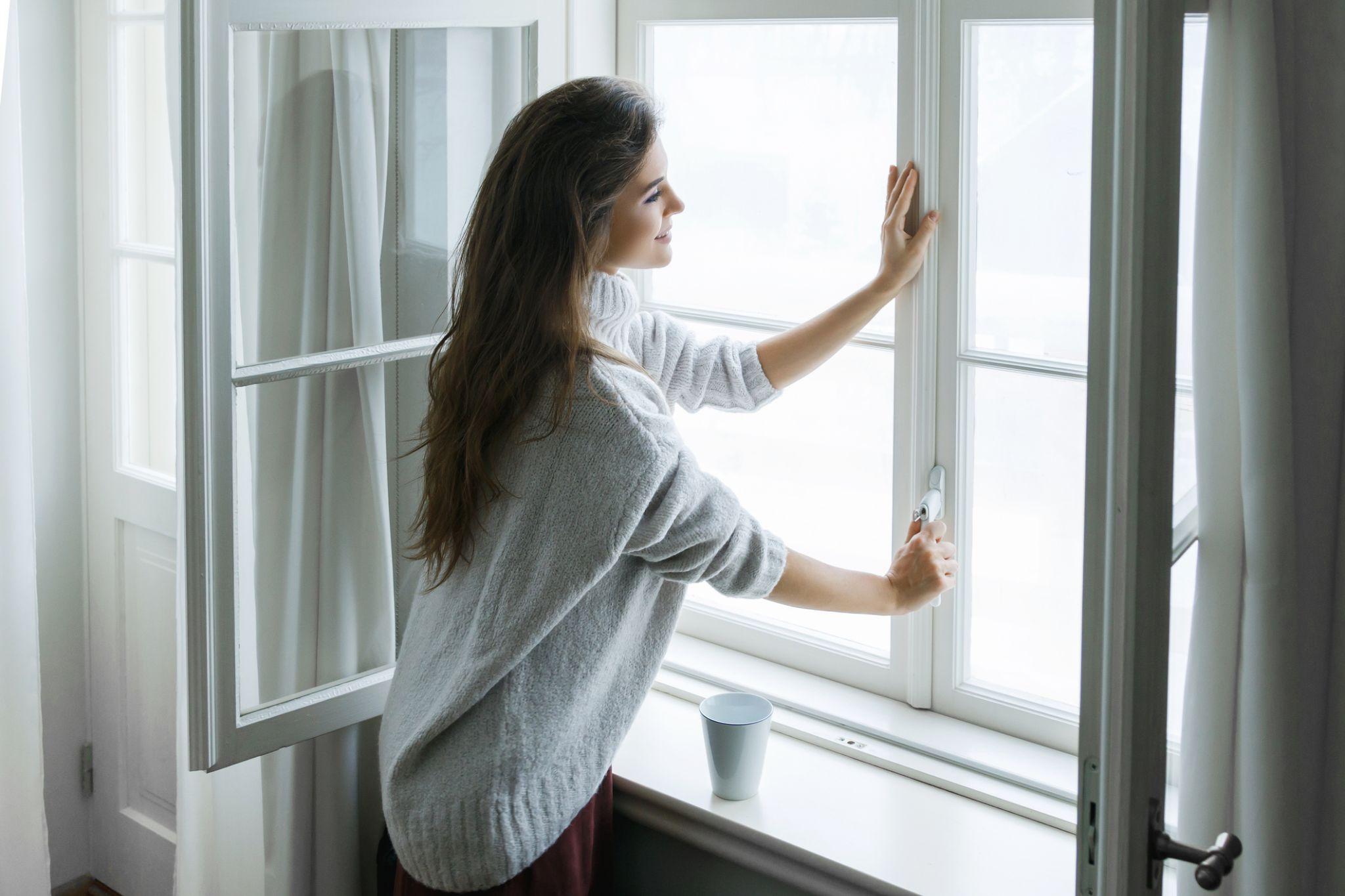 A homeowner closing a DraftLOCK vinyl window to improve energy efficiency, reduce drafts, and help lower home heating costs.