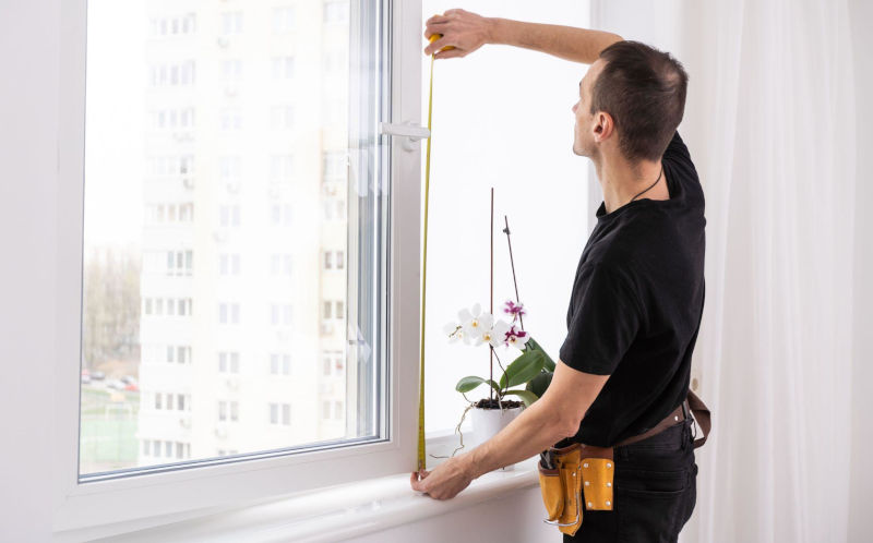 Window installer measuring a replacement window for workmanship